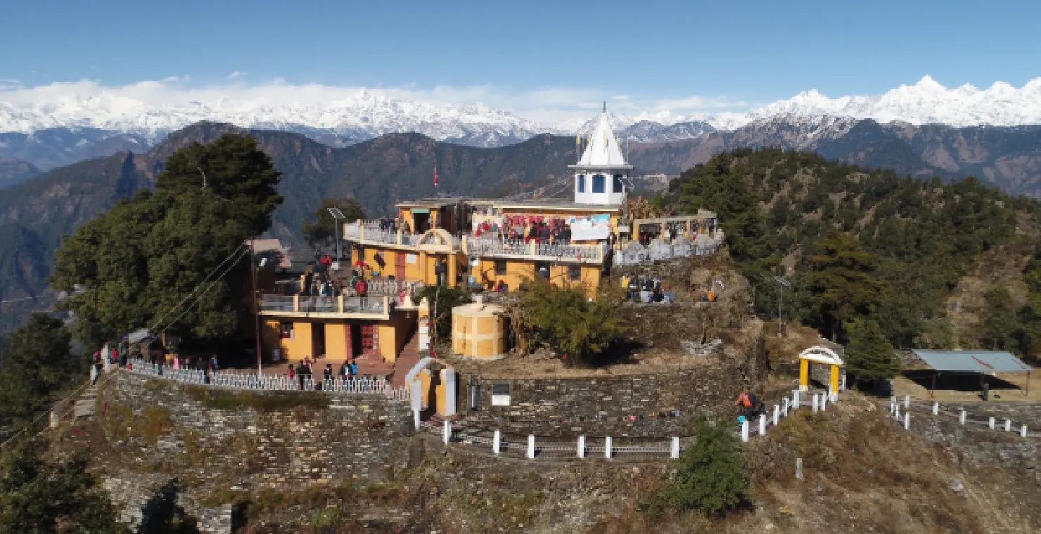 Aerial view of Kartik Swami Temple complex perched on ridge with snow-capped Himalayan peaks in background