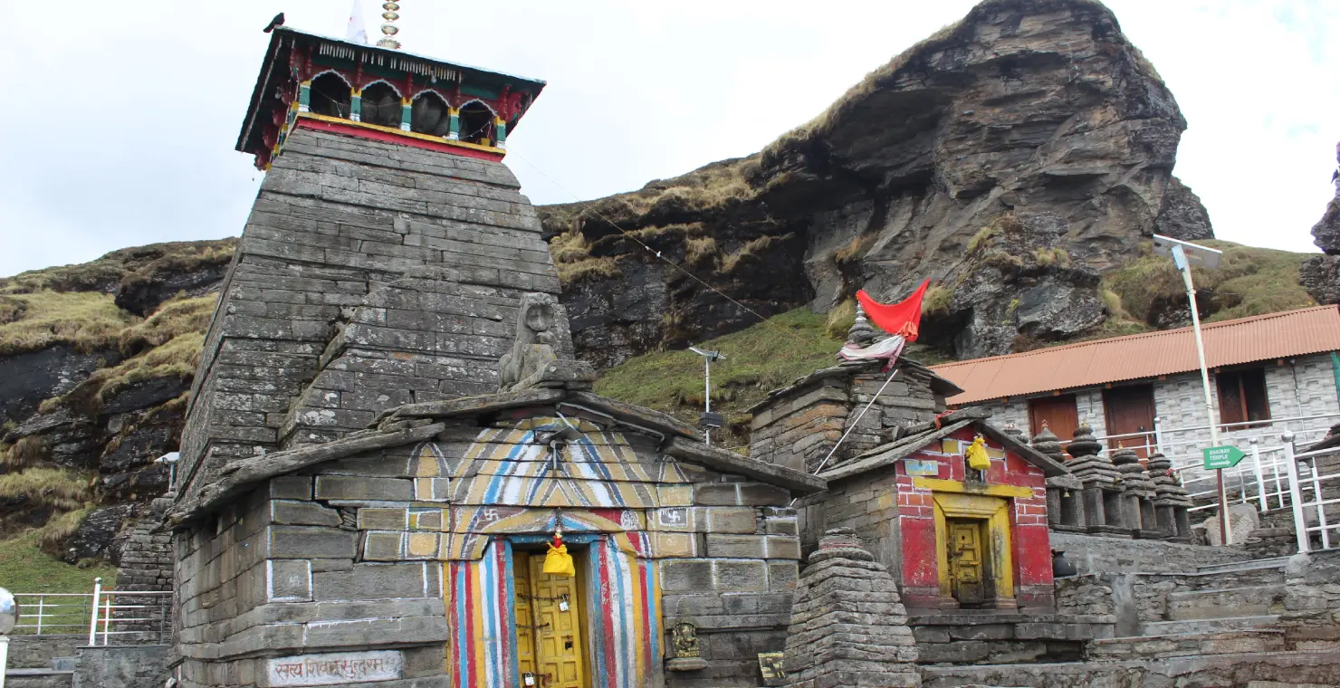 Ancient Tungnath Shiva Temple surrounded by Himalayan cliffs during Chopta trek